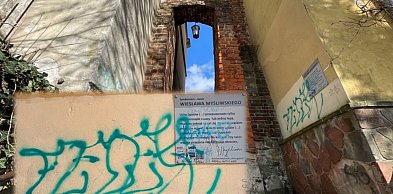 Ślady wandalizmu w Uchu Igielnym. Pomazana tabliczka z cytatem